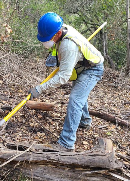 ECI employee grubbing out vegetation with hand tools