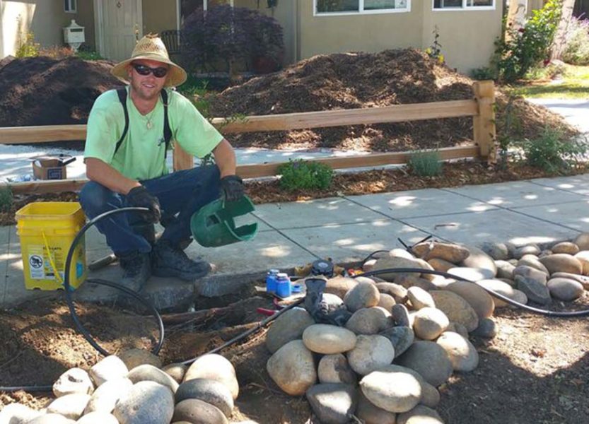 ECI employee holding irrigation tubing, monitoring an irrigation installation at a residence 